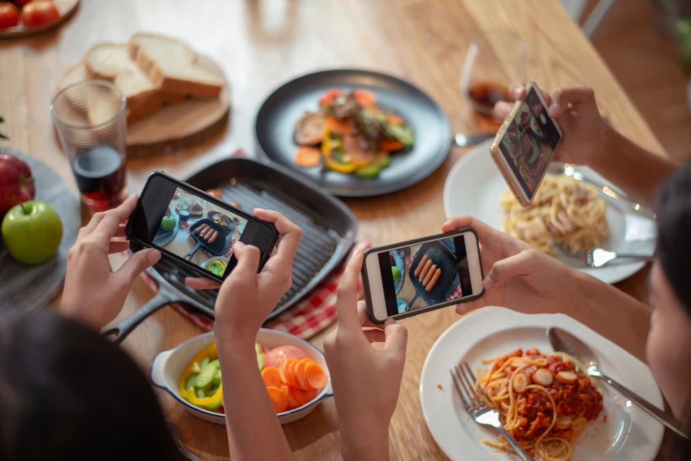 Clients de restaurant fotografiant plats enlloc de menjar 