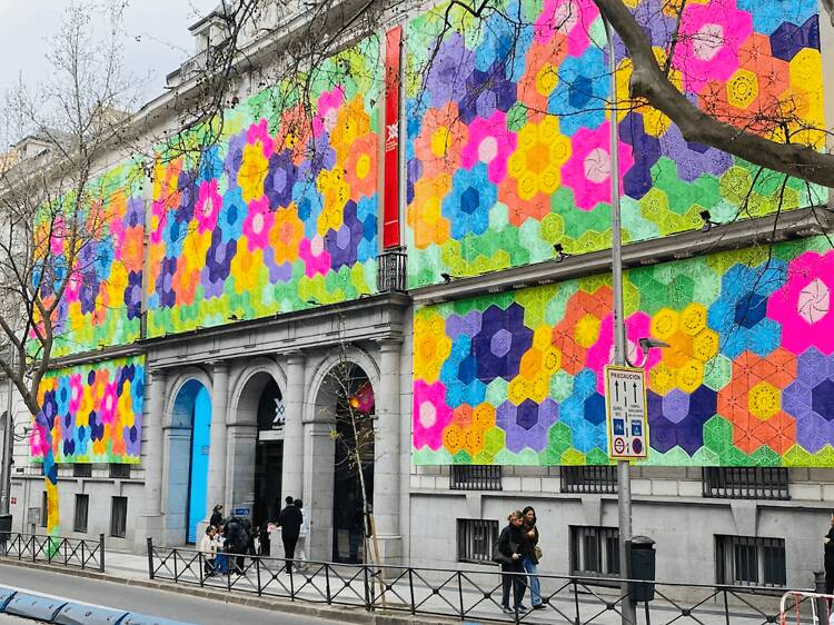 Una monumental instalación, como un crochet gigante, cubre la fachada de este edificio histórico en Madrid: 230.000 metros de rafia con flores tejidas por 200 mujeres artesanas