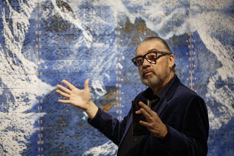 Artist Guillermo Bert in front of a piece of his artwork.