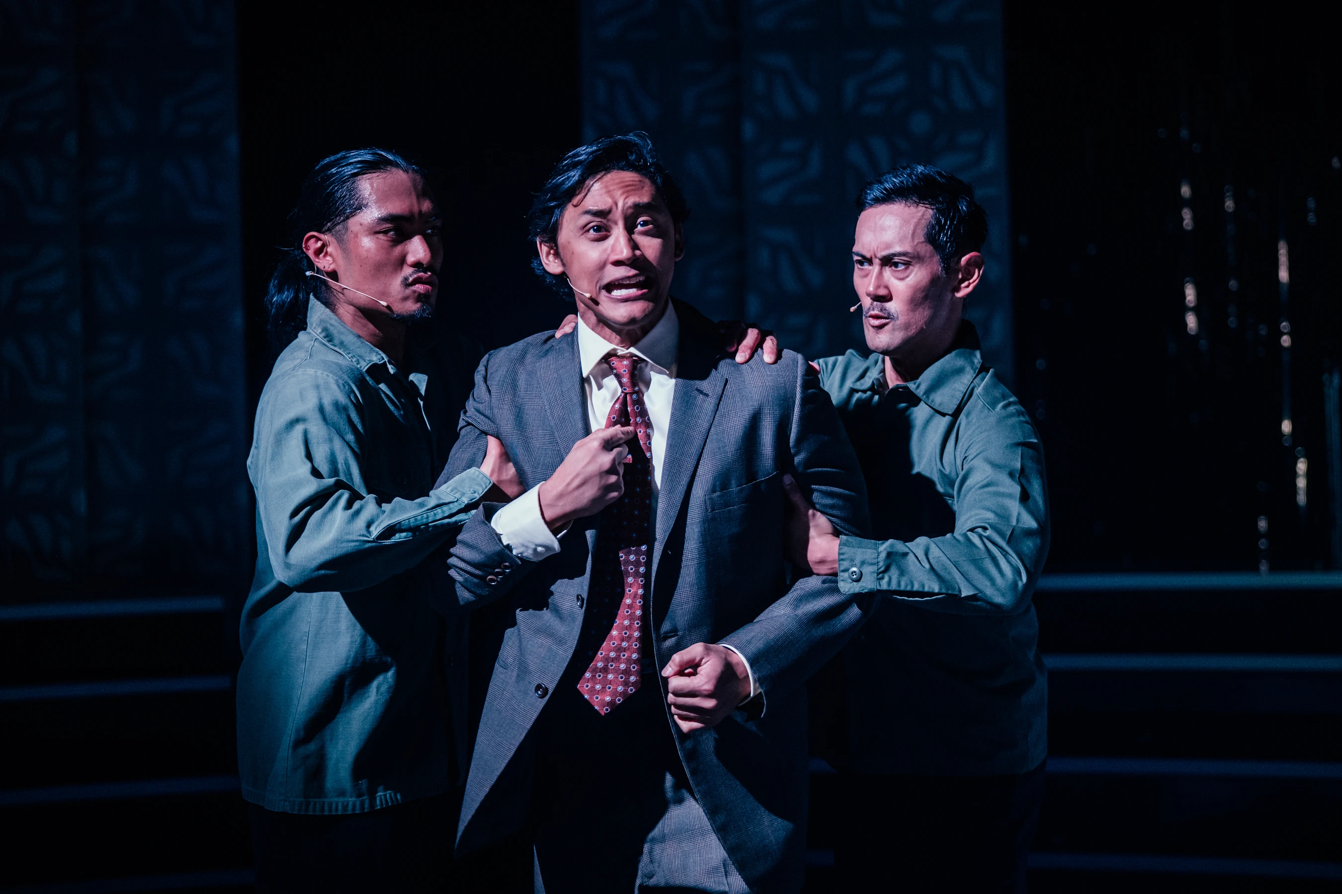 Two men restrain Joshua Dela Cruz as Ninoy Aquino in Here Lies Love.