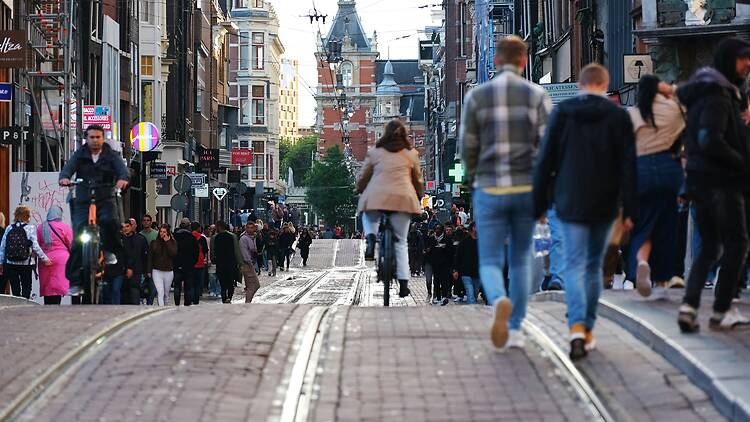 a crowd of people walking down a street next to tall buildings