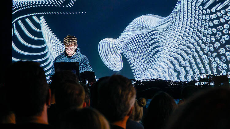 Mies soittaa tietokoneelta teknomusiikkia yleisön edessä klubilla Kuudes Linja Helsingissä