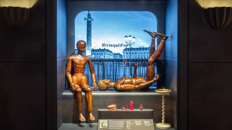 Model of a shop window featuring two wooden mannequins in ‘Schiaparelli: Fashion Becomes Art’