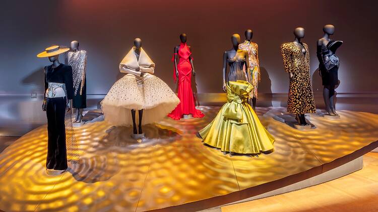 An oval platform displaying eight mannequins wearing Schiaparelli dresses