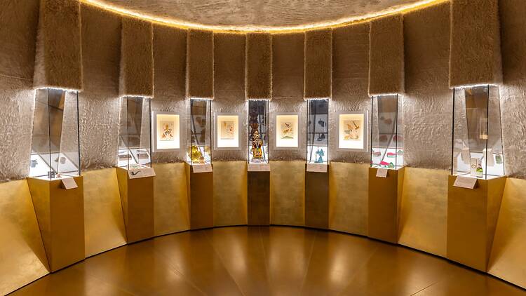 A curved gallery showcasing perfume bottle designs in ‘Schiaparelli: Fashion Becomes Art’