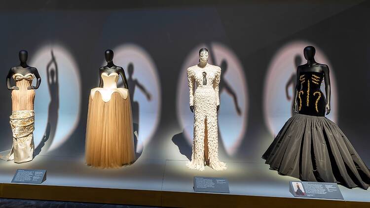 Four mannequins dressed in evening gowns in ‘Schiaparelli: Fashion Becomes Art’