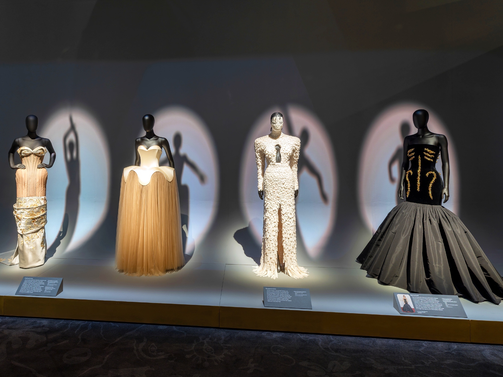 Four mannequins dressed in evening gowns in ‘Schiaparelli: Fashion Becomes Art’