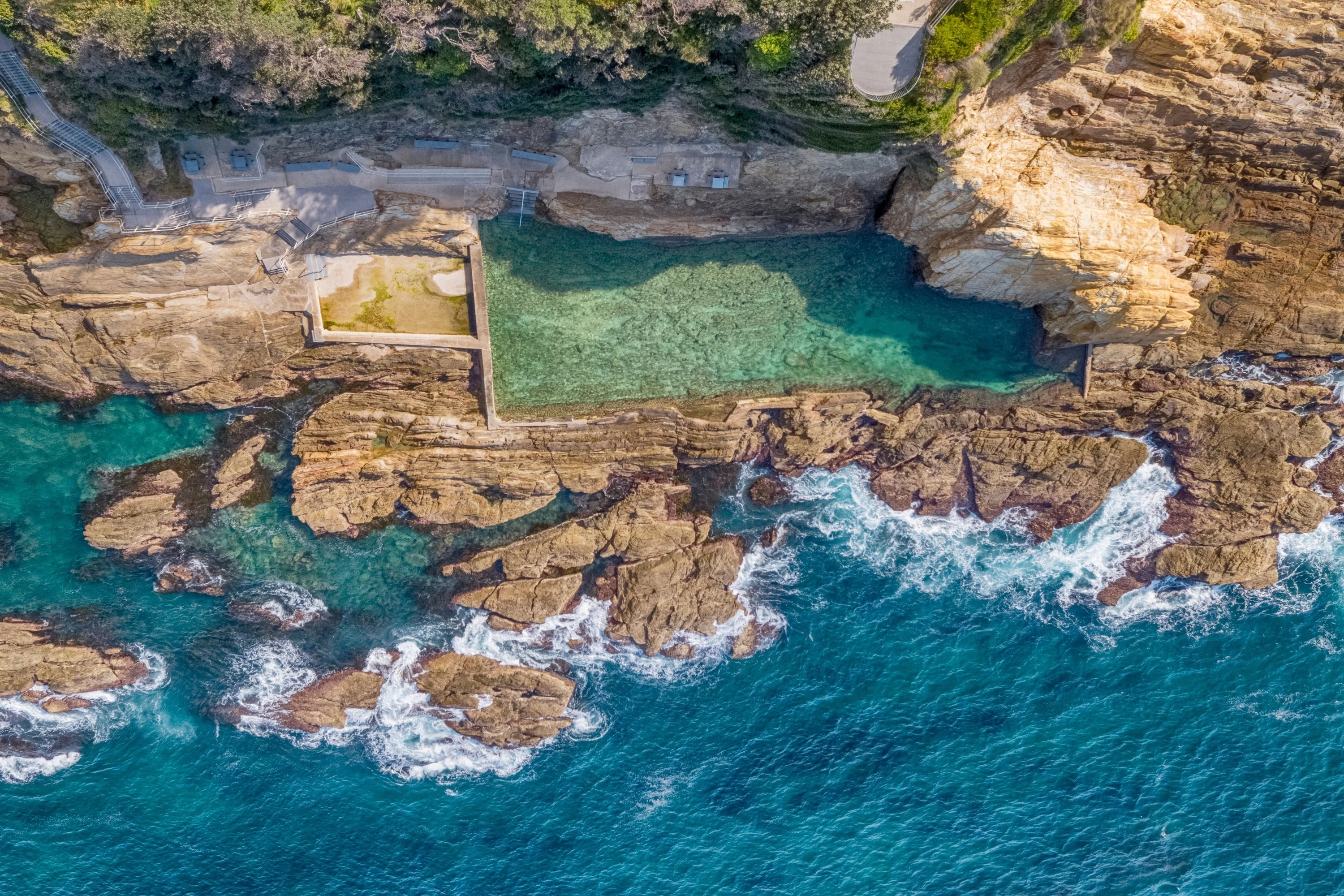Aerial overlooking Blue Pool ocean pool in Bermagui.
