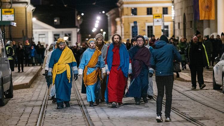 Jeesus kävelee saattajiensa seurassa Helsingin kadulla näytelmässä Via Crusis Jeesus kävelee saattajiensa seurassa Helsingin kadulla näytelmässä Via Crusis