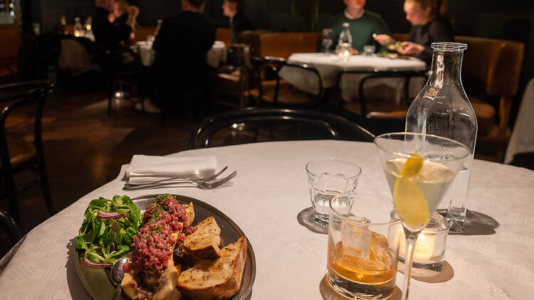 Valkoisella pöytäliinalla on annos luuydintä sekä laseja ravintolassa Grand Bar & Grill