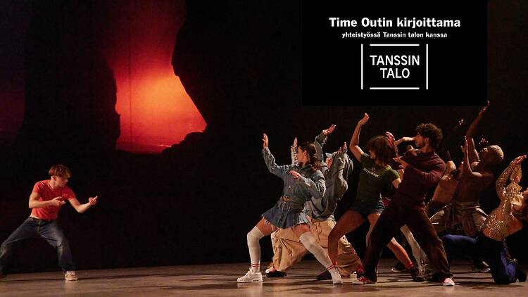 Ryhmä tanssijoita esittää lavalla dynaamista kohtaa yhdessä rivissä, yhden esiintyjän ollessa erillään vasemmalla, taustalla punaisena hehkuva valoprojektio.