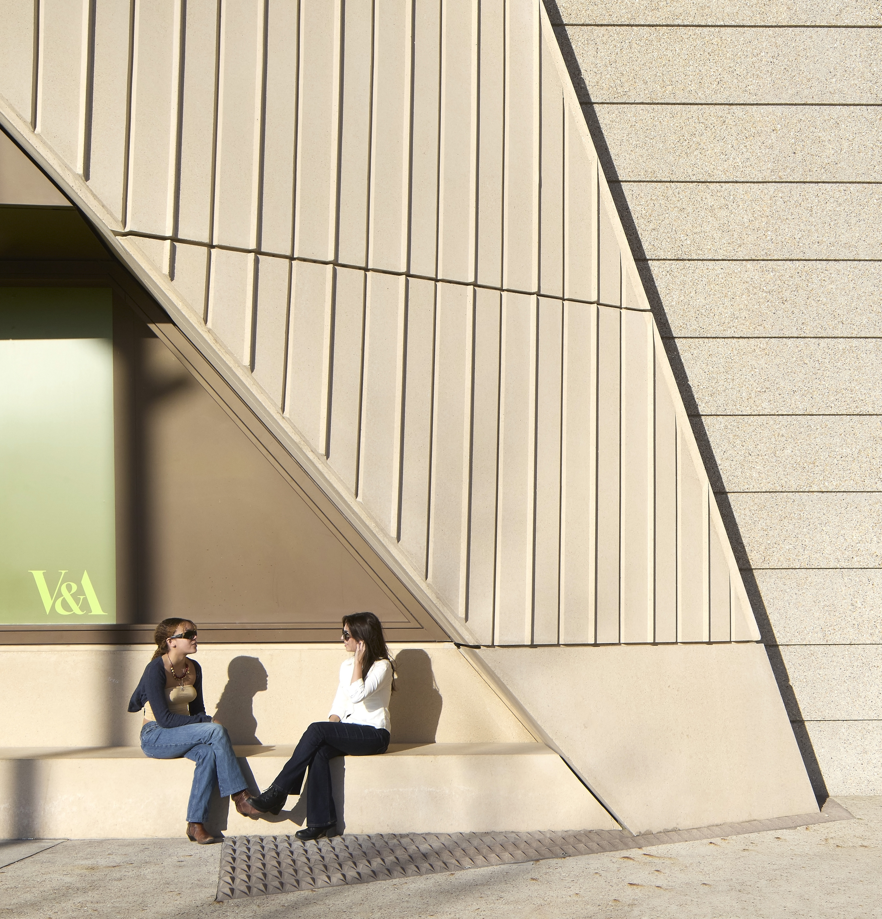 Two women sit chatting on built-in bench outside new museum