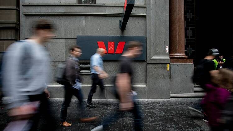 a group of people walking down a street next to a tall building