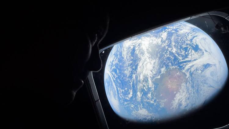 An astronaut peers out of one of the Orion spacecraft's main cabin windows, looking back at Earth, as the crew travels towards the Moon. An astronaut peers out of one of the Orion spacecraft's main cabin windows, looking back at Earth, as the crew travels towards the Moon.