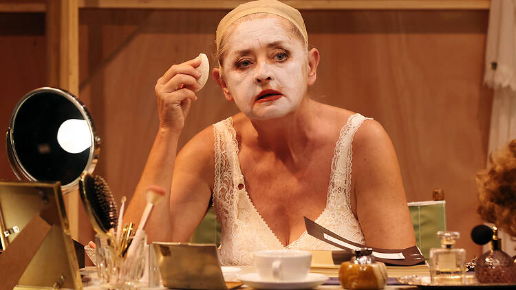 A woman putting on white stage make-up