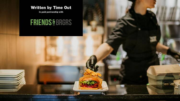 A chef places a plated burger on a restaurant counter