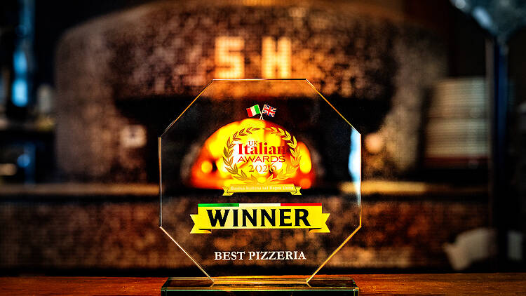 Best Pizzeria trophy in front of wood-fired oven