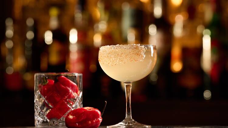 A cocktail in a coupe glass with peppers