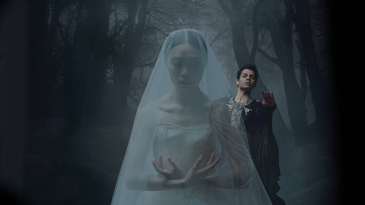 A man reaches toward a woman in a wedding dress.