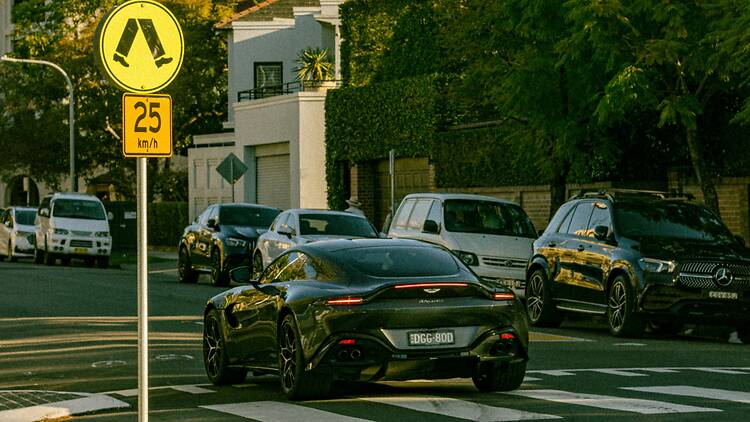 Car a yellow and black street sign and some cars