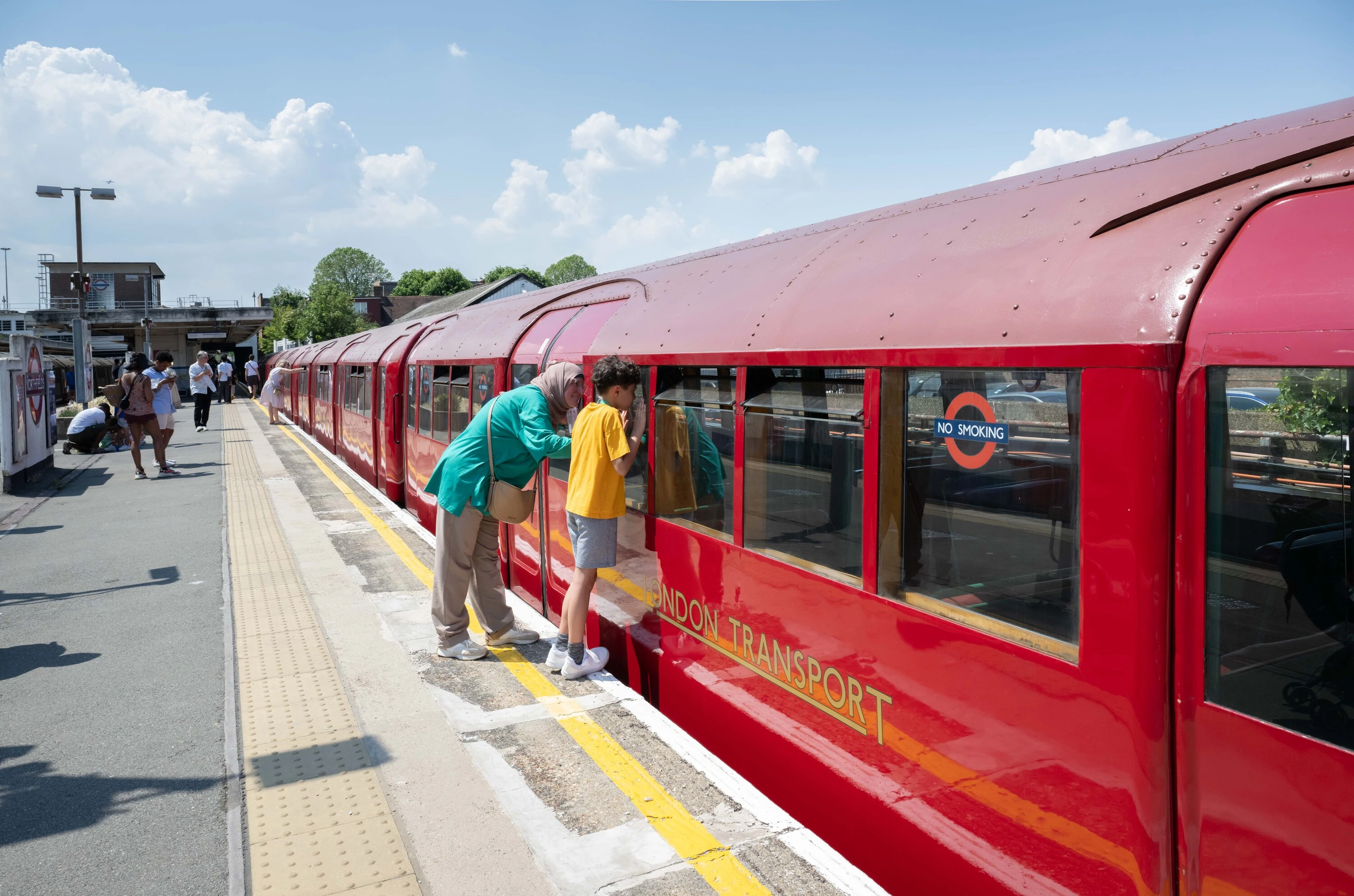 Mother and son looking into the 1938 vintage tube train window from platform