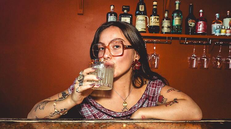 Female bartender sipping on cocktail behind the bar