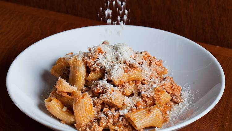 A plate of pasta being sprinkled by parmesan A plate of pasta being sprinkled by parmesan
