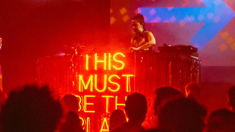 People dancing on dancefloor in front of DJ and disco ball