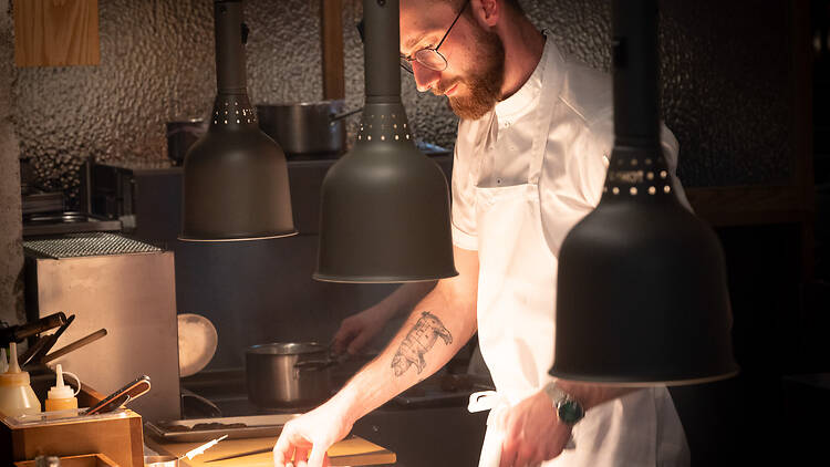 Keittiömestari kokkaa avokeittiössä ravintolassa Alma