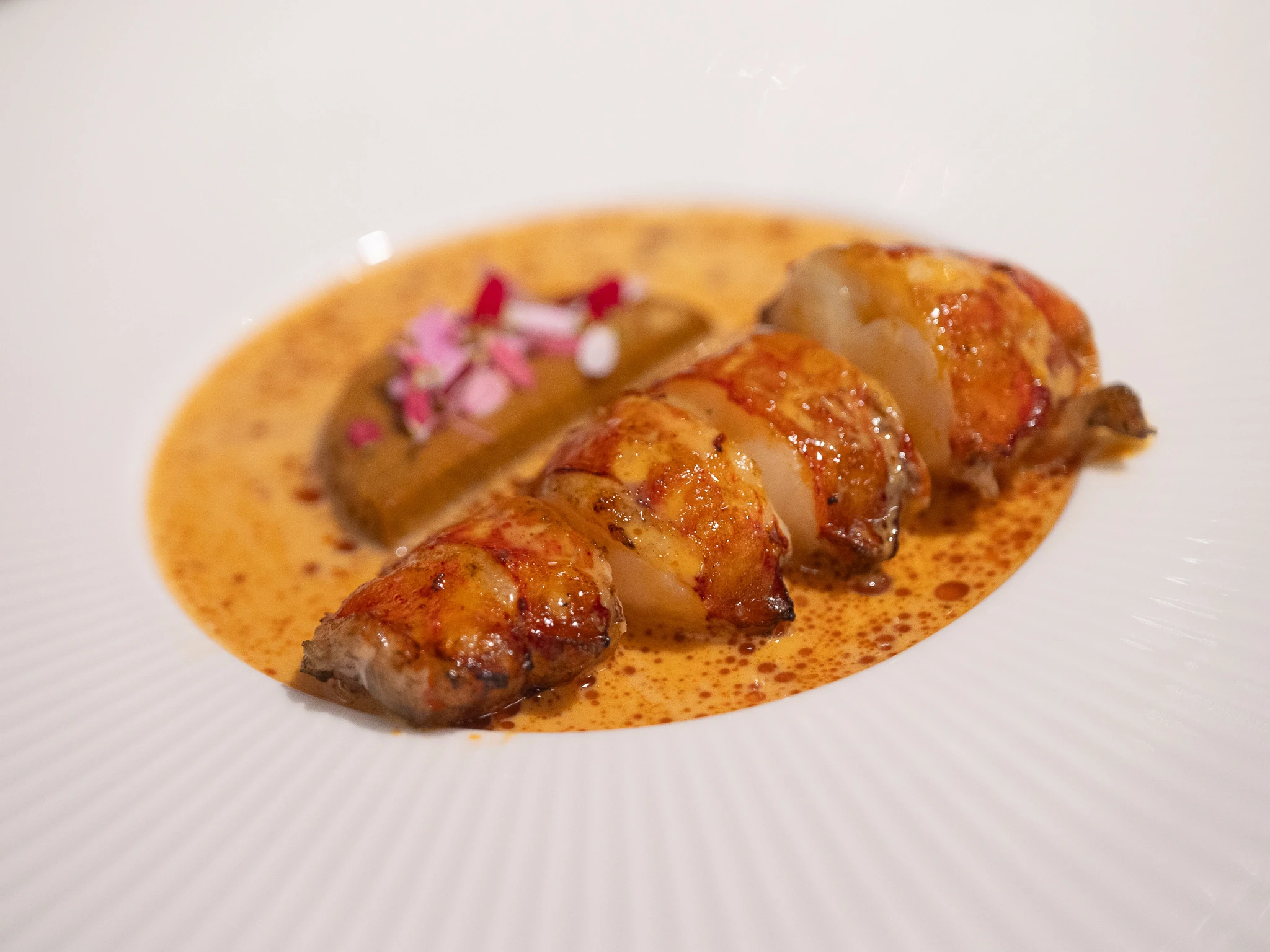 Hummerin pyrst&ouml; valkoisella lautasella oranssissa chipotle kastikkeessa 