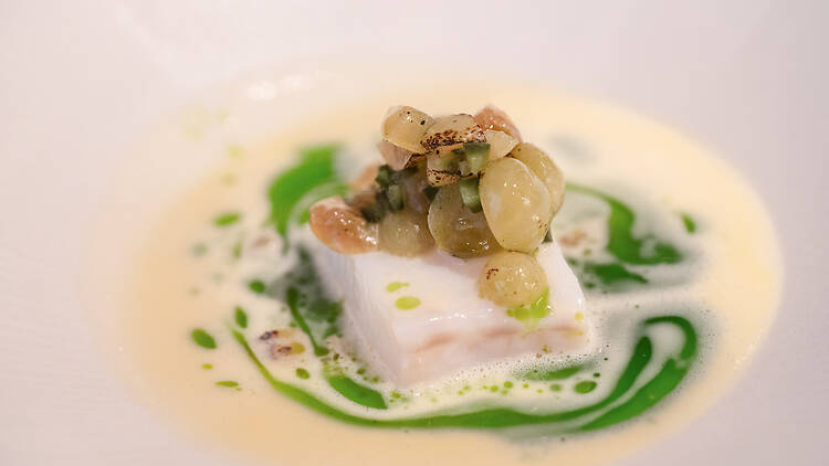 pala turskaa päällään viinirypäleitä valkoisessa kastikkeessa jossa on vihreitä viiruja