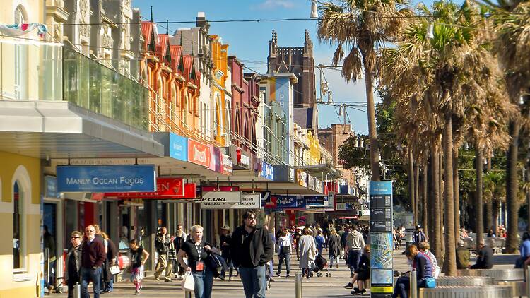 a group of people walking down a street next to tall buildings