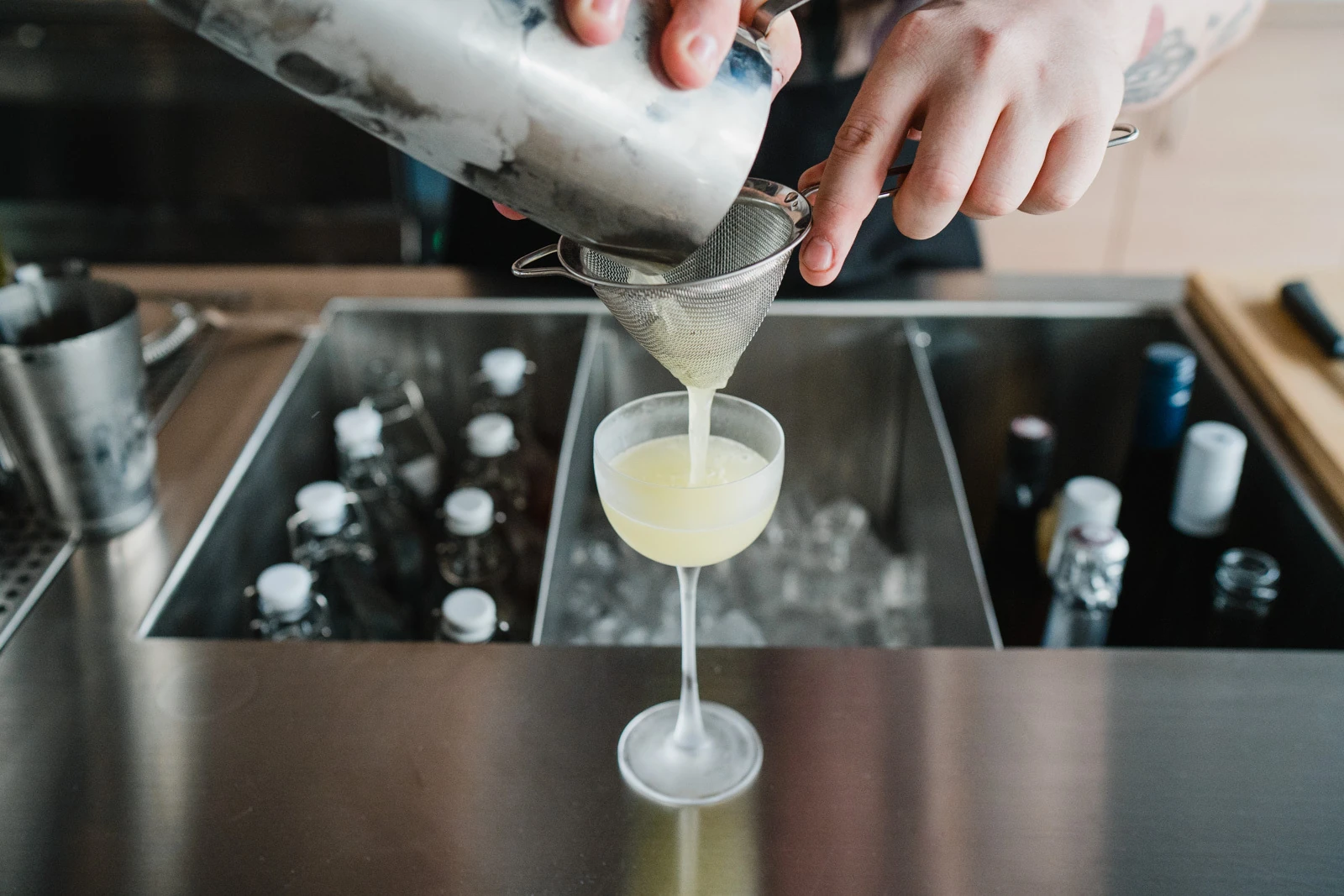 Bartenders hands pouring drink into stemmed glass