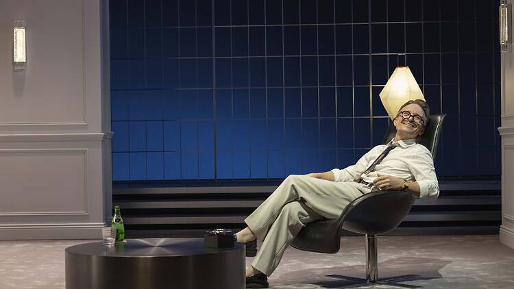 Damon Herriman in a chair on stage in 'Art'.