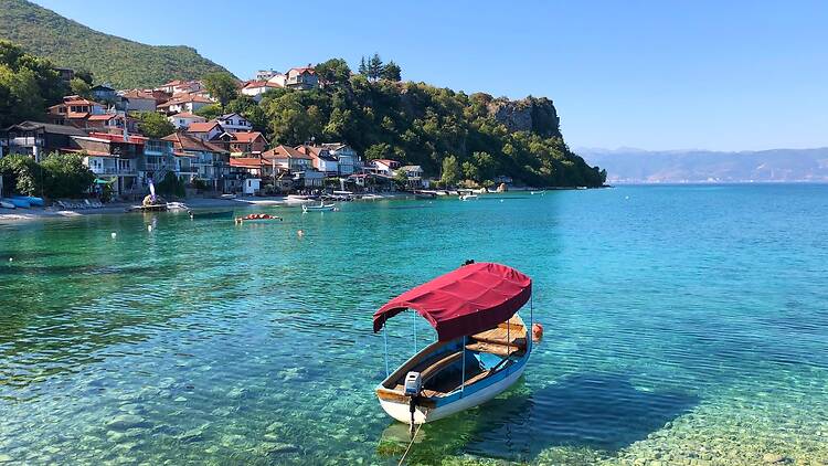 Beautiful little boat at the Lake Ohrid, North Macedonia. Trpejca fishing village on the left. Albania is visible in the background
