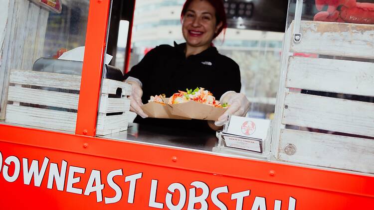 A person handing over a lobster roll