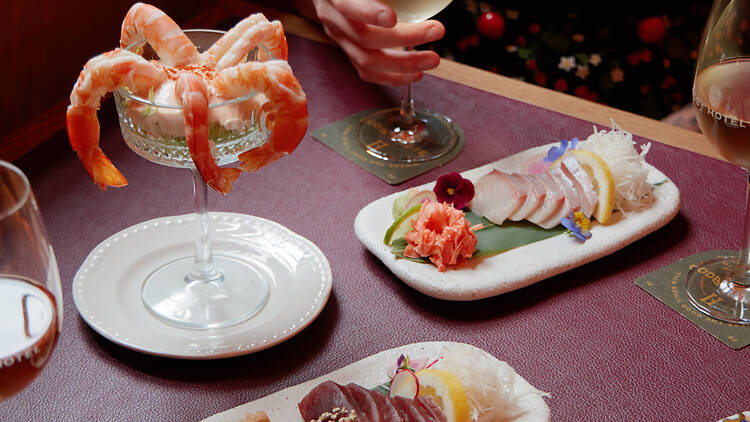 A table laden with sashimi, nigiri and a prawn cocktail.