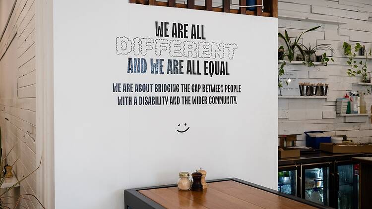 Motivational signage on a white wall at All Things Equal.