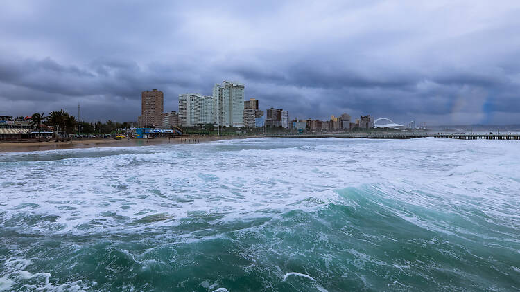 Waves crashing along the beachfront with Durbans skyline under a cloudy sky in South Africa