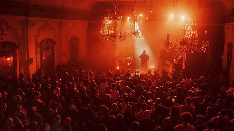 Full crowd watching a solo performer lit by a spotlight at Bush Hall