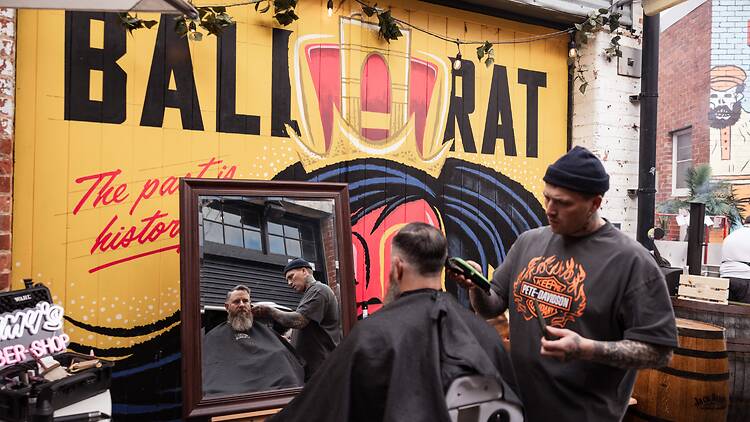 barber clips another man's hair and beard