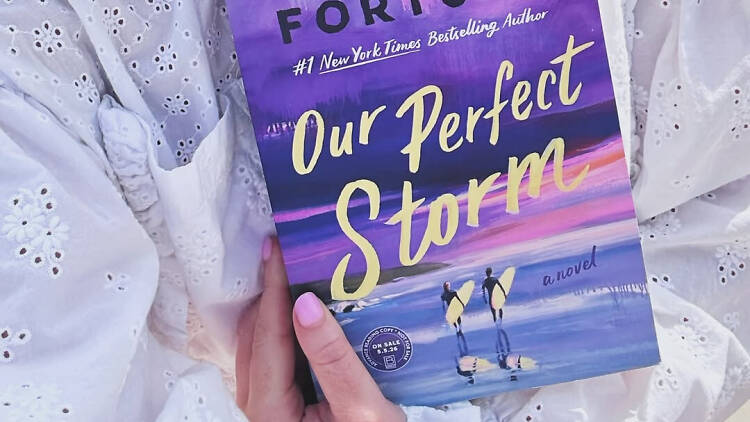 Carley Fortune holds a hardback copy of Our Perfect Storm