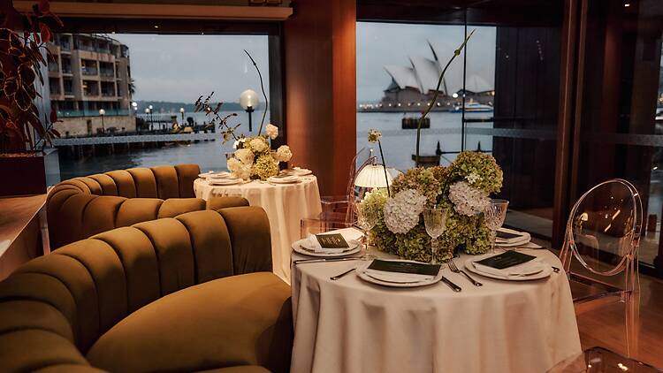 Park Hyatt Sydney A moody dining interior with floral arrangements on the table and Opera House views through the window