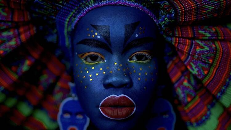 Atong Atem A woman's face painted blue.