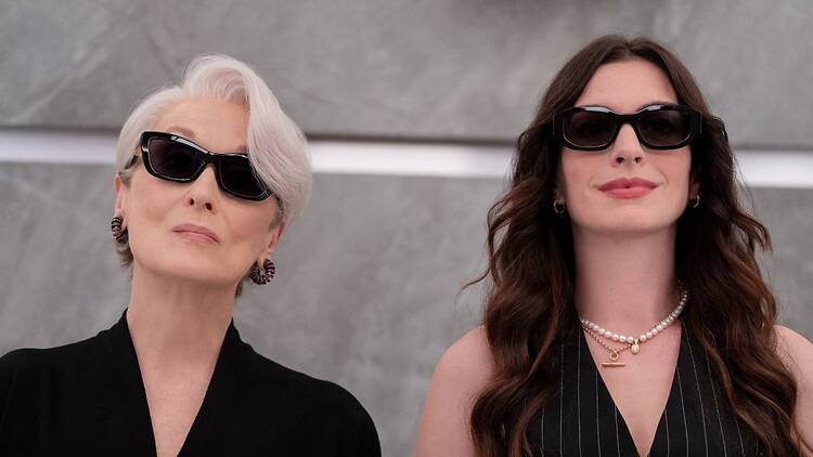 Meryl Streep ja Anne  Hathaway poseeraavat vierekkäin mustissa aurinkolaseissa