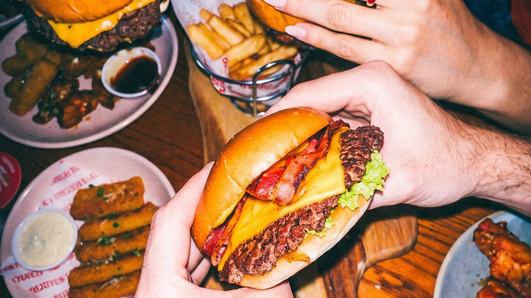 Someone holding a smash burger in front of other similar plates