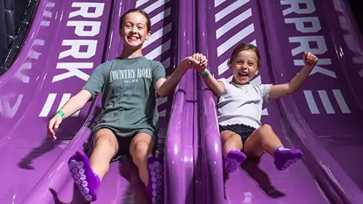Two kids on a purple slide.