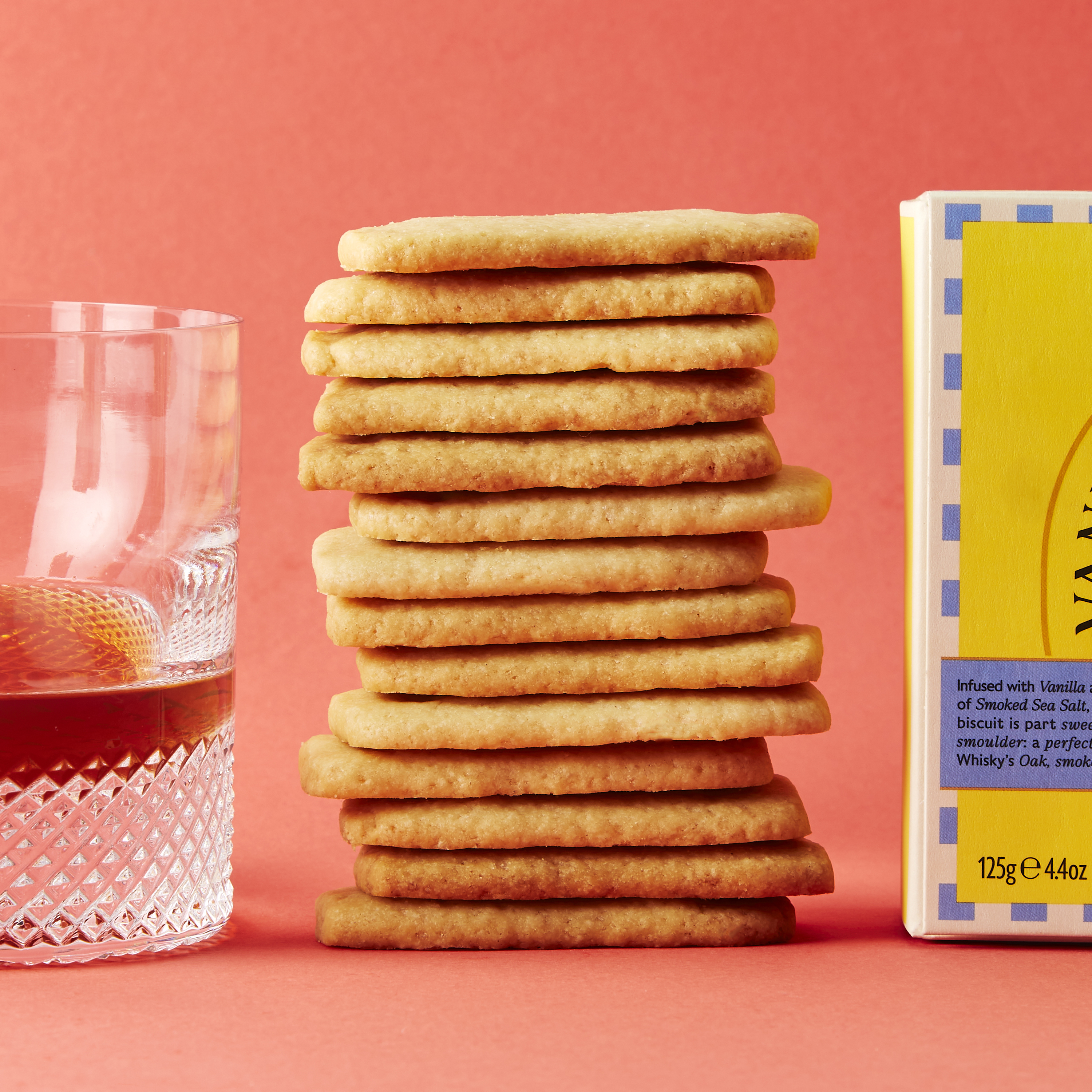 Stack of biscuits in between biscuit box and dram of whisky