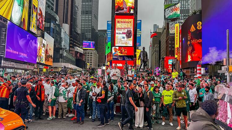 Soccer fans gather in Times Square waving flags and chanting during a public celebration ahead of a World Cup match