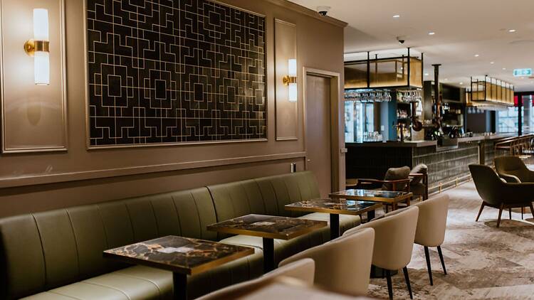 A low-lit restaurant interior with forest green booths